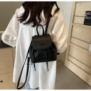 Detail view of black lychee leather mini backpack with drawstring and metal ball accents