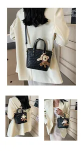 Detailed close-up of black woven texture tote bag with a brown monkey charm and slim strap