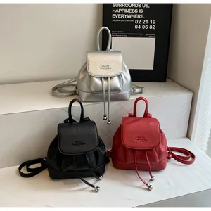 Close-up of mini bucket backpacks in silver, black, and red with pebbled leather texture