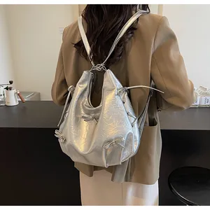 Silver wrinkled metallic backpack with cute bow details shown on a model in a cafe