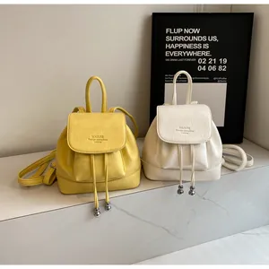 Detail of mini leather backpacks in yellow and beige with drawstring and metal charm