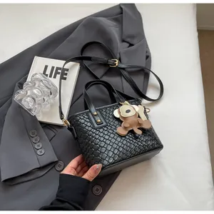 Detailed texture of black woven tote bag with a cute cartoon monkey leather charm