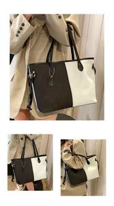 Détail d'un grand sac cabas en denim bicolore avec poignées en cuir et étiquette décorative