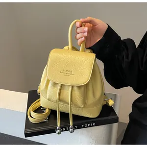 Detail of yellow soft leather mini backpack with drawstring and silver metal ball accents
