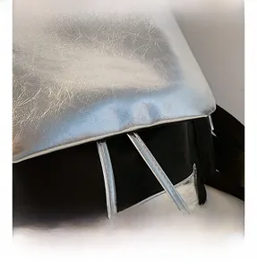Detail of silver metallic textured fabric with black drawstring and refined stitching