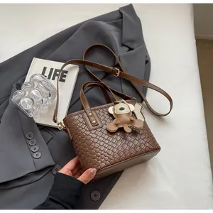 Detail of brown woven tote bag with adjustable strap and cute bear charm decoration
