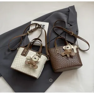 Detail of woven texture crossbody bag with adjustable strap and cute leather monkey charm