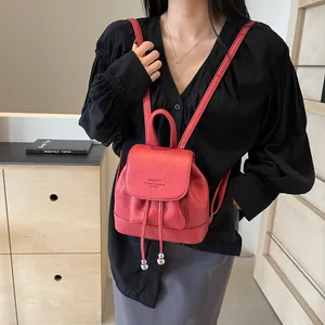 Red pebbled leather mini backpack with drawstring and flap closure shown on model