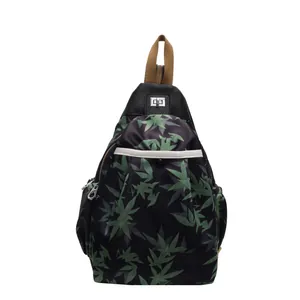 Black nylon crossbody bag with green leaf patterns and brown woven handle top view
