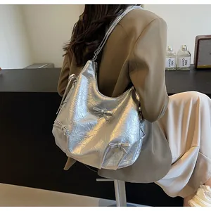 Close-up of a silver metallic hobo bag featuring 3D bow accents and soft pleated texture