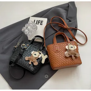 Detail of woven texture tote bags in black and brown with cute monkey charms