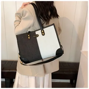Detail of minimalist black and white canvas tote bag with gold logo and wide strap