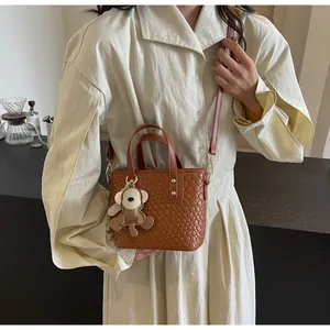 Detail of woven texture on brown mini tote bag with adjustable strap and monkey charm