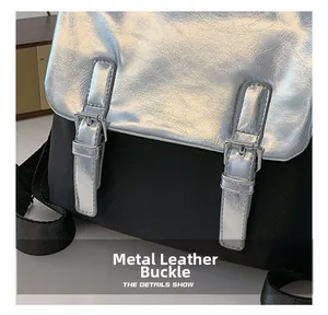 Détail de la boucle en métal argenté et du rabat brillant sur un sac à dos contrasté