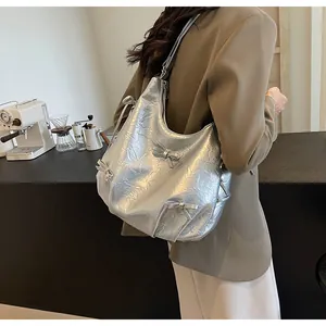 Detail of silver metallic tote bag with bows and wrinkled texture shown in a cafe