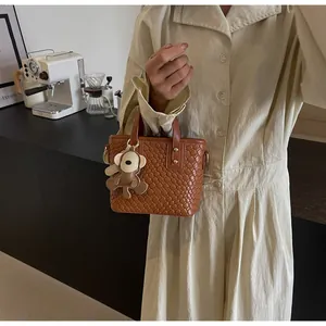 Detail of woven brown tote bag with metal studs and a cute monkey keychain