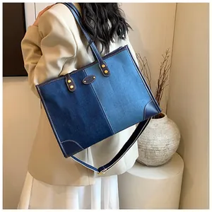 Detail view of denim patchwork tote bag showing blue leather trim and golden metal buckle
