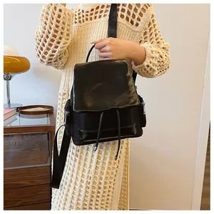 Detailed view of black faux leather backpack with drawstring closure and metal zippers