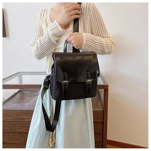 Détail d'un sac à dos noir avec rabat, doubles boucles métalliques et bandoulière