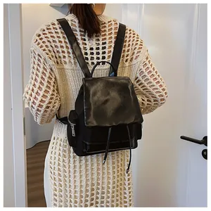 Model wearing a large black contrast backpack with drawstring and flap closure details