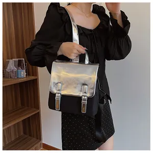 Détail du sac à dos avec rabat argenté métallique et corps en nylon noir sur une étagère
