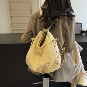 Chic beige pleated backpack with bow detail shown on a model in a casual setting