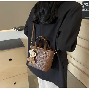 Detail of dark brown woven tote bag with adjustable strap and cute monkey charm
