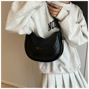 Close-up of black quilted hobo bag with glossy finish and metal hardware on shoulder strap