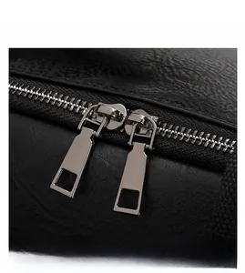 Detail view of the durable dual metal zippers and textured black PU leather backpack