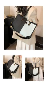 Detailed view of large tote bag with contrast denim panels and gold rivet hardware