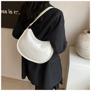 Close-up of quilted pattern on white crescent underarm bag with glossy finish