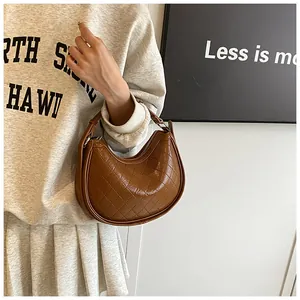 Detail of a brown quilted leather crescent underarm bag with smooth zipper closure
