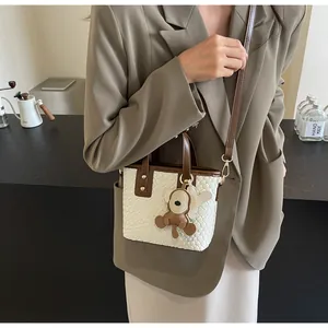 Detail of woven white tote bag with brown monkey charm and adjustable shoulder strap