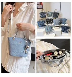 Dettaglio della borsa a tracolla in denim con catena in metallo e ciondolo cane