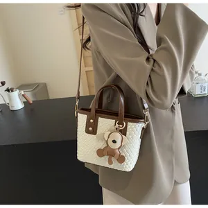 Detail of woven bucket bag featuring brown leather handle and cute monkey charm
