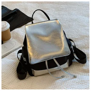 Flat lay of a stylish black and silver backpack with drawstring and metal flap detail