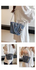 Dettaglio della borsa a secchiello in denim blu con catena e ciondolo a cane