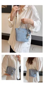 Dettaglio della borsa a secchiello in denim con catene d'argento e ciondolo a palloncino