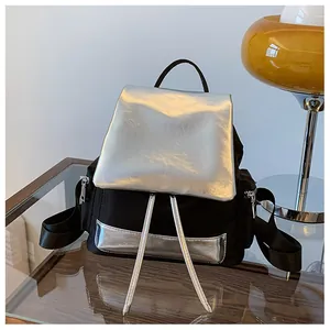 Detail shot of the glossy silver contrast flap and side zipper pocket on a black backpack