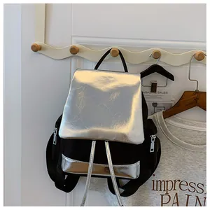 Detail of contrast color backpack with silver flap and side zipper pocket shown on hook