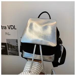 Detail view of contrast nylon backpack with shiny silver flap and side zipper pockets