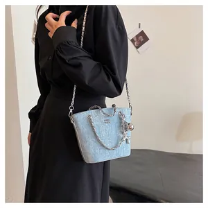 Dettaglio della borsa a secchiello in denim celeste con catena e ciondolo a palloncino