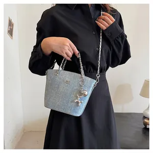 Dettaglio borsa a secchiello in denim azzurro con catena argento e ciondolo a cane