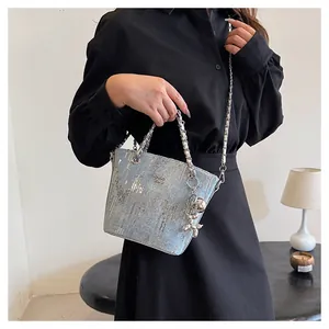 Borsa a secchiello in denim con paillettes blu, tracolla a catena e ciondolo a cane