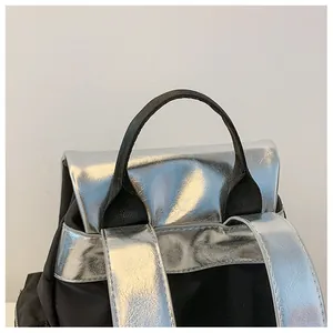 Detail of contrast color backpack showing black woven handle and silver metallic shoulder straps