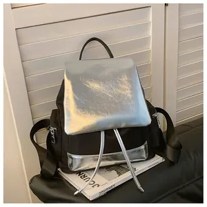 Detail view of the metallic silver mirror-effect flap and drawstring on the black backpack