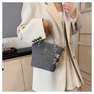 Dettaglio borsa a tracolla in denim grigio con catena argento e ciondolo cane