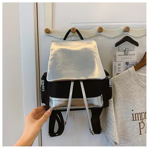 Detail of color-block backpack with silver metallic flap and decorative drawstrings