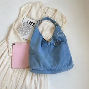 Light blue denim tote bag with white floral rose embroidery and spacious hobo design