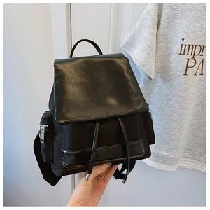 Detail of the black nylon backpack with flap closure, drawstring, and side zipper